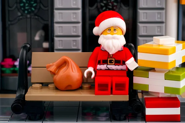 Lego Kerstman zittend op de bank buiten met stapel gif — Stockfoto
