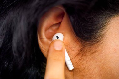 Kadın parmağı kulaklığına dokunuyor. Yakın plan..