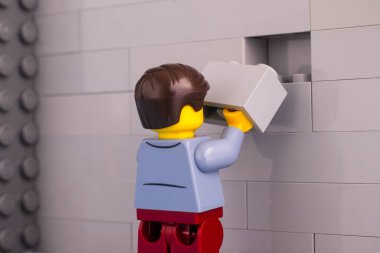 Tambov, Rusya Federasyonu - Haziran 07, 2020 Lego adam minifiki tuğlaları gri duvarı bitirmeye hazır