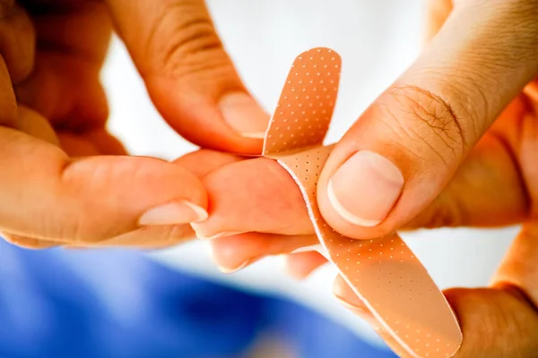 Woman putting adhesive bandage on her finger. Closeup