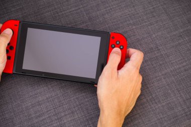 Tambov, Rusya Federasyonu - 22 Haziran 2019 Nintendo Switch video oyun konsolunu tutan kişi. Gri arkaplan.