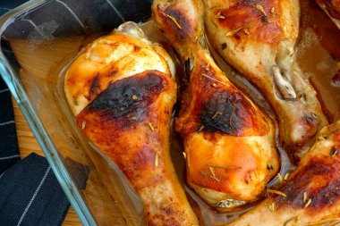 Kızarmış tavuk budu ve cam fırın tepsisi masanın üstünde. Yakın plan.