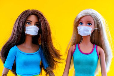 Tambov, Rusya Federasyonu - 12 Haziran 2020 Sarı arka planda tıbbi maskeli iki Barbie bebek. 