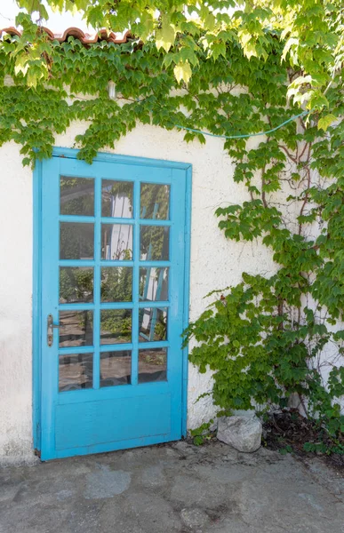 青いドアとウィンドと伝統的な白いギリシャの家のファサード ストック画像