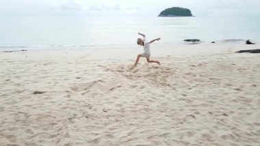 Maskeli küçük çocuk plajda koşuyor.