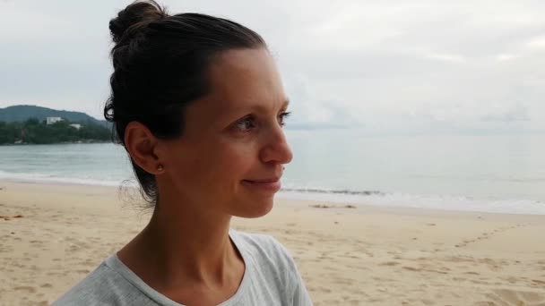 Young woman stands on the beach and looks at sea — Stock Video