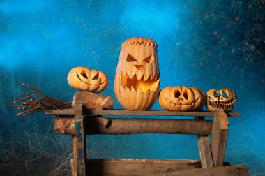 Bir mistik peri sisin içinde bir ahşap tahta üzerinde farklı boyutlarda dört balkabağı. Cadılar Bayramı - Jack-o-fener sembollerin korkunç. Tatil kavramı parlak Cadılar Bayramı aile. Yatay closeup fotoğraf