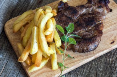 Izgara domuz biftek ile kızarmış patates ve kekik ahşap arka plan üzerinde