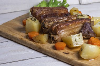 Beyaz ahşap arka plan üzerinde kekli patates ile kavrulmuş domuz kaburgası, Doğu mutfağı