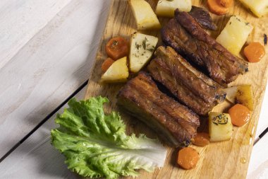 Beyaz ahşap arka plan üzerinde kekli patates ile kavrulmuş domuz kaburgası, Doğu mutfağı