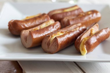 Beyaz ahşap arka plan üzerinde sarı peynir ile kavrulmuş sosis