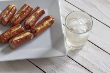 Sarı peynir ve beyaz ahşap arka plan üzerinde soda bir bardak ile kavrulmuş sosis
