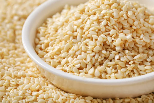 bowl of healthy sesame seeds on sesame seeds background - close up