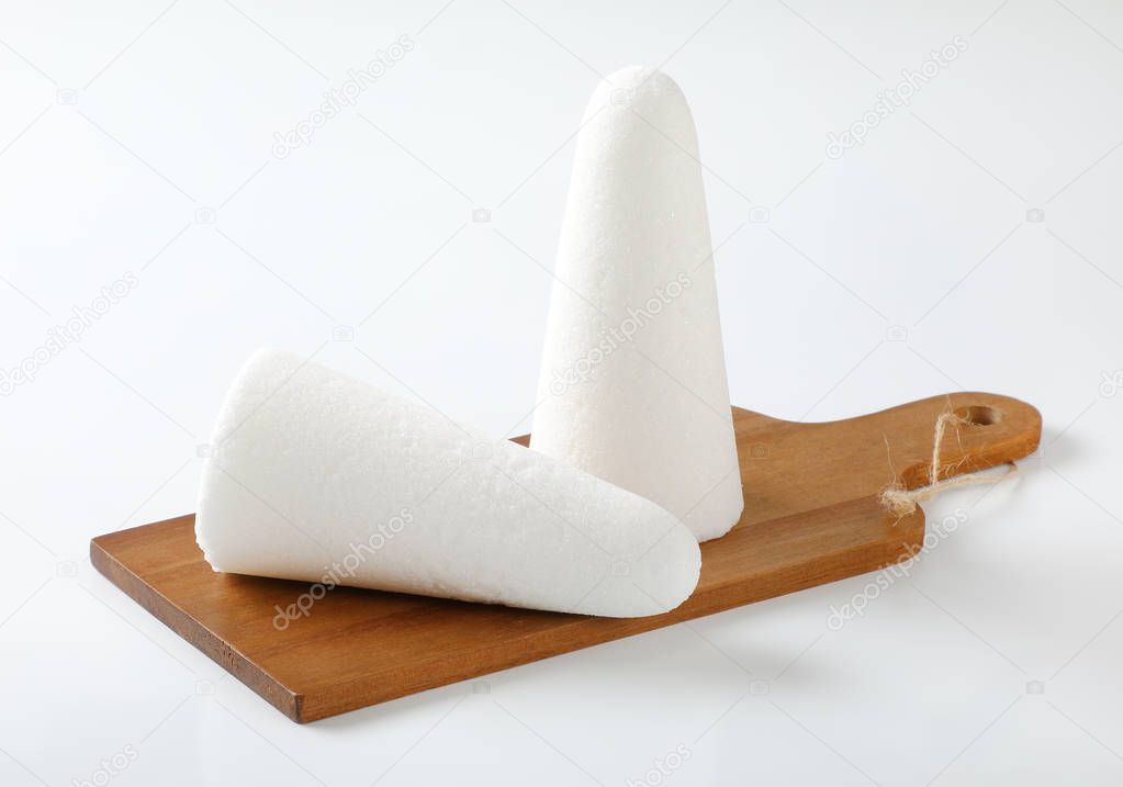 two white sugar loaves or cones on wooden cutting board