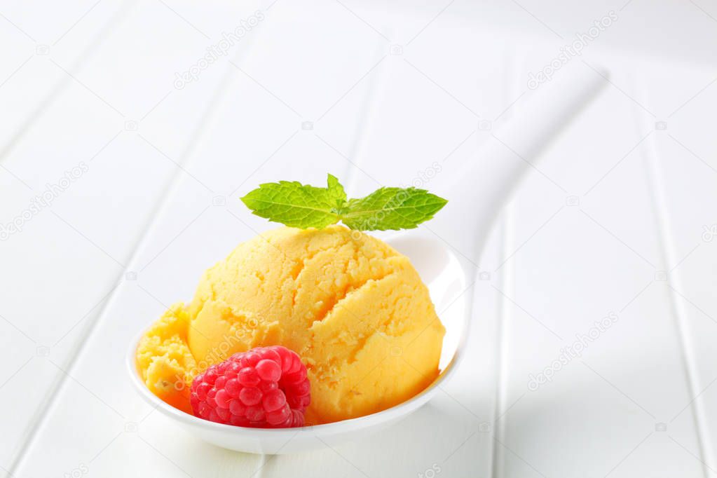 Scoop of yellow ice cream on porcelain spoon