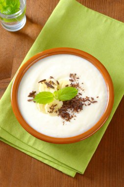 Dilimlenmiş muz ve rendelenmiş çikolata ile pürüzsüz süt puding kase