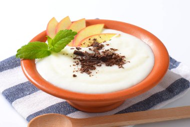 Elma dilim ve rendelenmiş çikolata ile süt puding kase