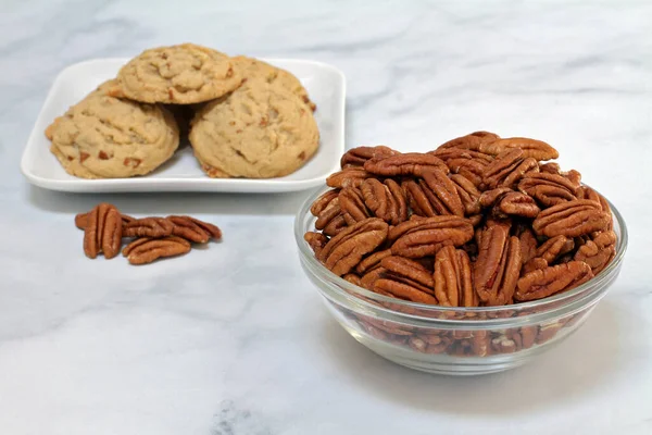 Pecan halves in a glass bowl with selective focus on bowl. Macro with copy space on granite tabletop.