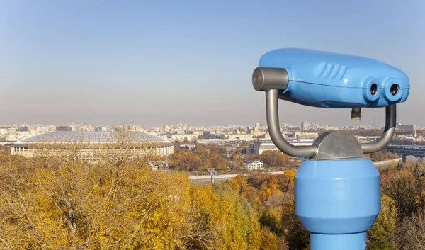 Touristic telescope viewer (binoculars) and view of central Moscow from Sparrow Hills or Vorobyovy Gory observation (viewing) platform-- is on a steep bank 85 m above the Moskva river, or 200 m above sea level. Moscow, Russia