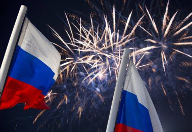 Gökyüzünde patlayan renkli havai fişekler ve rüzgarda gökyüzüne doğru sallanan Rusya bayrağı. Vatansever bir sembol olarak Rus dalgalı bayrağıüç renk  