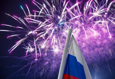 Gökyüzünde patlayan renkli havai fişekler ve rüzgarda gökyüzüne doğru sallanan Rusya bayrağı. Vatansever bir sembol olarak Rus dalgalı bayrağıüç renk  