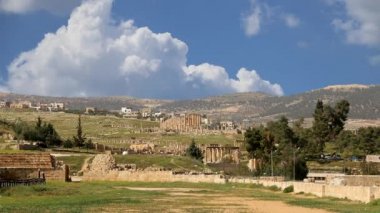 Ürdün 'ün Jerash şehrindeki (Gerasa of Antiquity) Roma harabeleri, hareket eden bulutların arka planına karşı başkent ve en büyük Jerash Valiliği, Ürdün