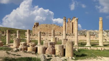 Ürdün 'ün Jerash şehrindeki (Gerasa of Antiquity) Roma harabeleri, hareket eden bulutların arka planına karşı başkent ve en büyük Jerash Valiliği, Ürdün
