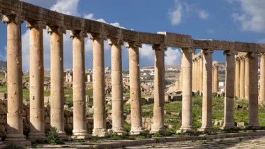 Ürdün, Gerasa 'da (Jerash) hareket eden bulutların arka planına karşı Forum (Oval Plaza). Forum, M.S. 1. yüzyılda inşa edilen Colonnaded Caddesi 'nin başlangıcında asimetrik bir plazadır. 