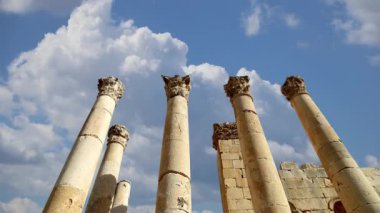 Ürdün 'ün Jerash şehrindeki Roma Sütunları (Antik Gerasa) hareket halindeki bulutların, başkentin ve en büyük Jerash Valiliği kentinin arka planına karşı 