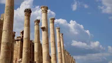 Ürdün 'ün Jerash şehrindeki Roma Sütunları (Antik Gerasa) hareket halindeki bulutların, başkentin ve en büyük Jerash Valiliği kentinin arka planına karşı 