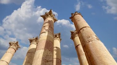 Ürdün 'ün Jerash şehrindeki Roma Sütunları (Antik Gerasa) hareket halindeki bulutların, başkentin ve en büyük Jerash Valiliği kentinin arka planına karşı