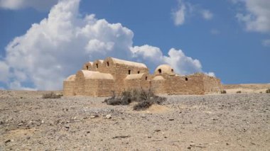 Amman yakınlarındaki Amra Çölündeki Kureyir (Qasr) Çöl Kalesi, hareket eden bulutların arka planına karşı, Ürdün. Ünlü freskleri olan dünya mirası..  