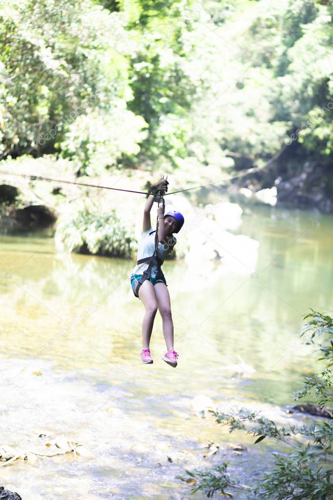 Happy Girl  in-motion on zipline in tropical jungle rainforest Tree Canopy