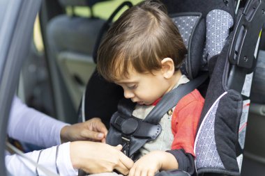 Mutlu Anne oğlunu arabada emniyet kemeri tutturmak için yardım