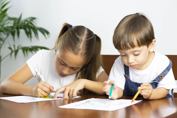 Söt flicka och pojke sitter vid sitt skriv bord målning — Stockfoto