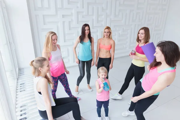 Gruppe junger Frauen mit einem kleinen Mädchen bei einem Chat nach einem Fitnesstanzkurs — Stockfoto