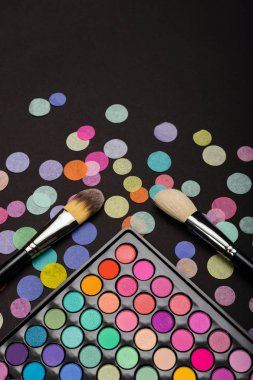 Makyaj fırça makyaj paleti siyah arka plan üzerinde renkli konfeti ile