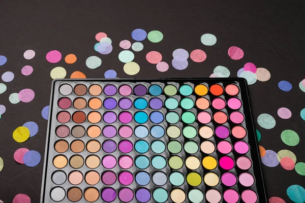 Primer plano de la paleta de sombras de maquillaje con confeti en negro —  Fotos de Stock