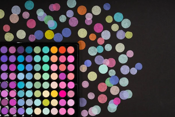 Make-up palette with confetti on black texture — Stock Photo, Image