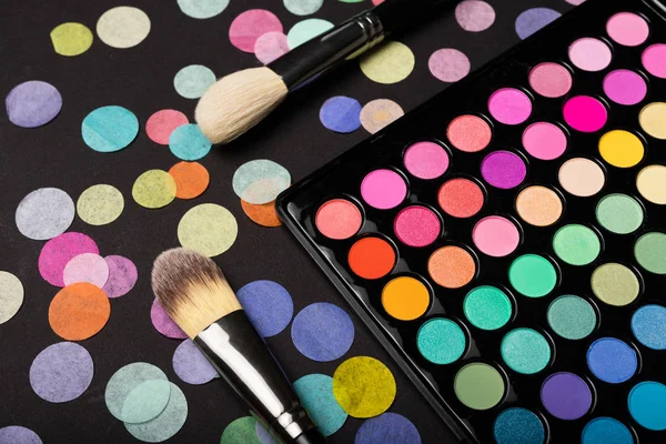 Make-up eyeshadow palette with brushes on back background with confetti — Stock Photo, Image