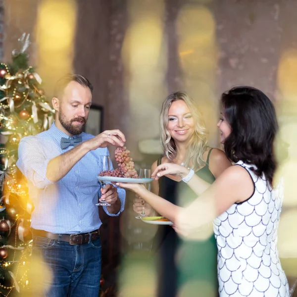 Jóvenes tomando algunas frutas con champán mientras celebran en la fiesta de Año Nuevo — Foto de Stock