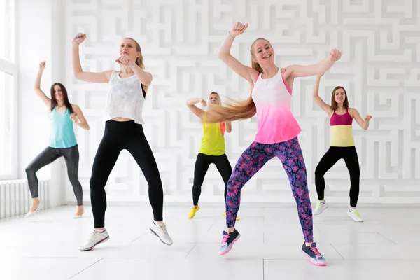 Группа молодых женщин, танцующих с поднятыми руками во время занятий фитнес-танцами — стоковое фото