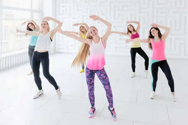 Группа молодых женщин, позирующих с поднятыми руками во время занятий фитнес-танцами — стоковое фото
