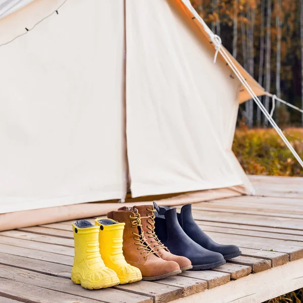 Three pair of shoes near a canvas tent — Stock Photo, Image