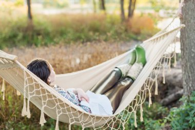 Genç kadın bir hamakta açık havada sonbaharda yalan