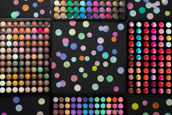 Paletas de maquillaje cosmético con confeti de colores dispersos sobre fondo negro — Foto de Stock