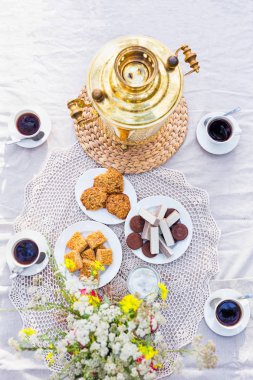 Yukarıdan semaver, kahve fincanı, tatlılar ile tabloda görüntülemek