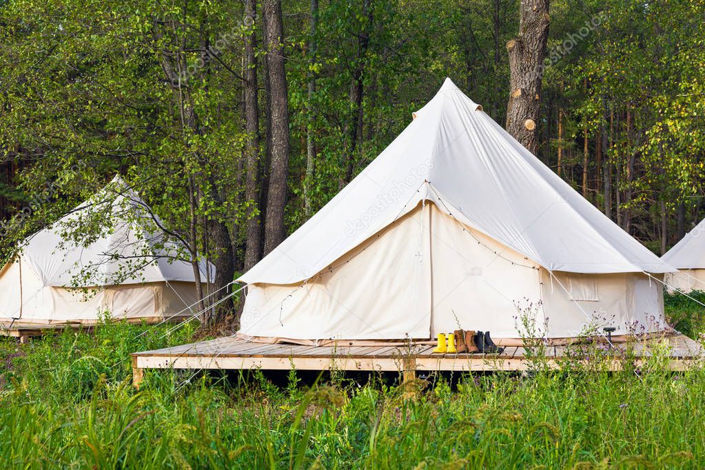 Two canvas bell tents outdoors at forest