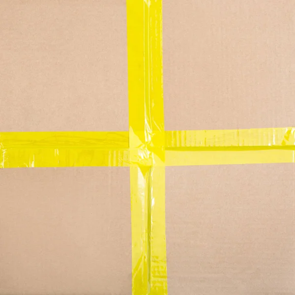 Cardboard background with a yellow sticky tape — Stock Photo, Image