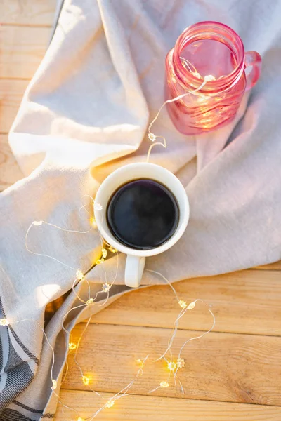 Ansicht der Kaffeetasse mit schönen Lichtern im Einmachglas auf einem Holztisch — Stockfoto